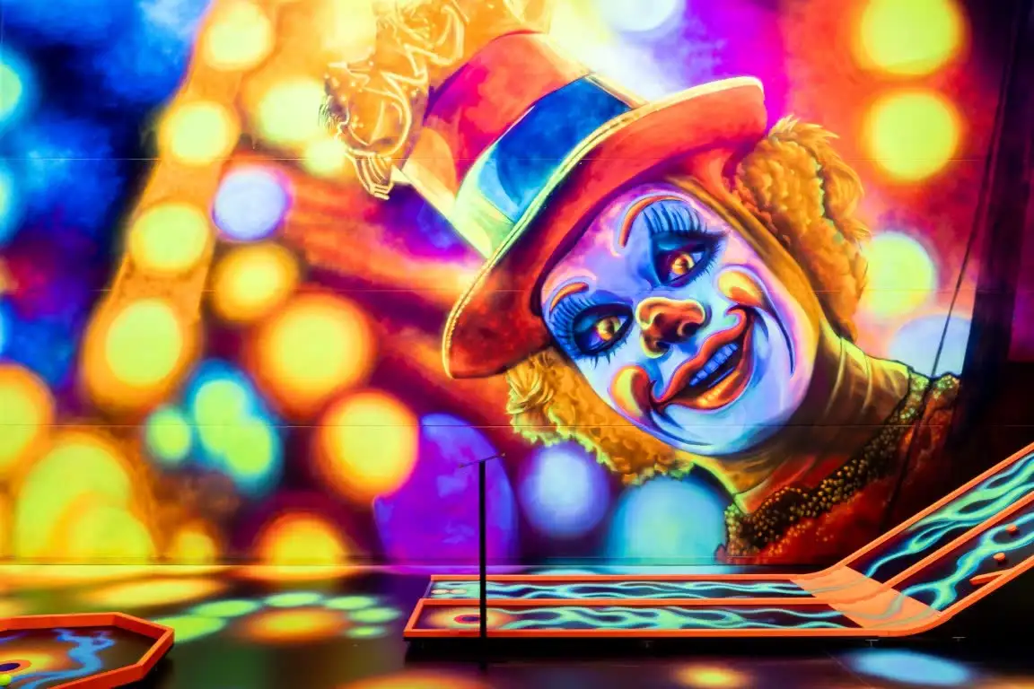 Clown mit Zylinder, davor eine leuchtende Bahn.